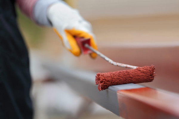 Metal painting. Worker painting steel tube with paintroller selective focus