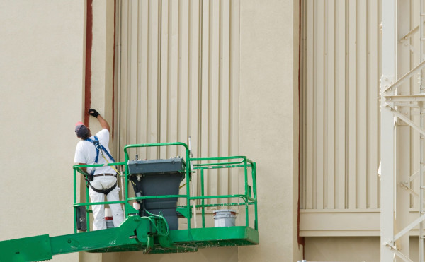 Painter on Lift. Paint contractor painting while on a lift.